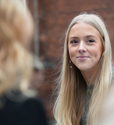 en pige som kigger ind i kamraet og smiler